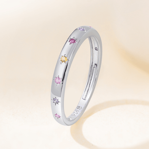 Silver ring with colorful gemstones on a soft beige background