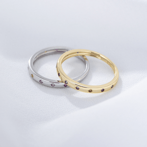 Two rings, one gold and one silver, with embedded stones on a light gray background