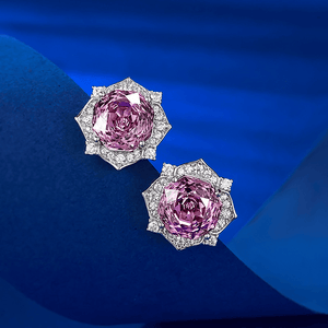 Pair of pink gemstone earrings on a blue fabric background
