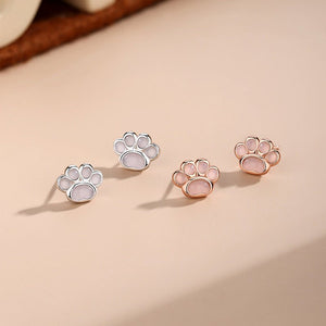 Paw print earrings in silver and rose gold on a beige background