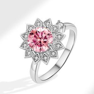 A gold-colored fidget spinner ring with a central pink gemstone and surrounded by clear stones, designed to resemble a sunflower.