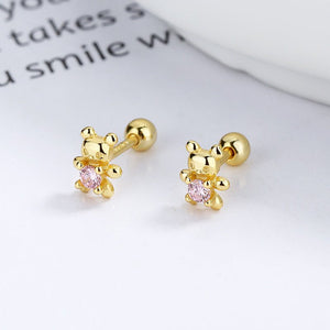 Gold teddy bear earrings with pink gemstones on a white surface.