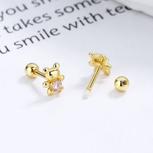 Gold earrings with a pink gemstone on a white surface