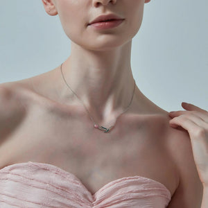 Woman wearing a delicate necklace with a minimal background