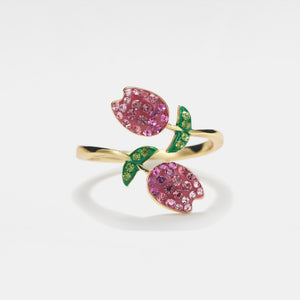 Gold ring with pink gemstone flowers on a white background