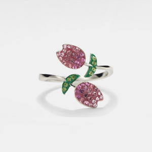A bypass ring with a gold plating, featuring two pink tulip flowers adorned with cubic zirconia, set in a white background.