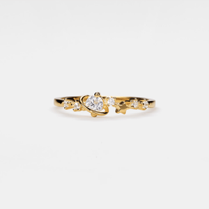 Gold ring with a heart-shaped center stone on a white background