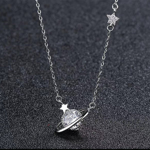 Silver necklace with a planet and star pendant on a dark textured background