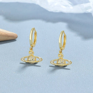 Gold earrings with a brand logo on a light blue background