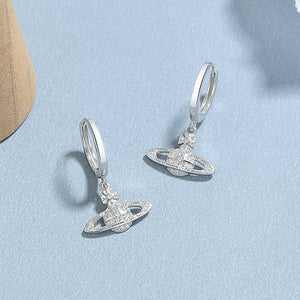 Silver earrings with intricate designs on a light blue background