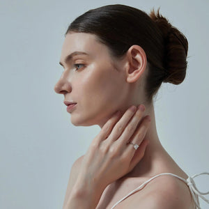 Woman wearing a diamond ring on a plain background