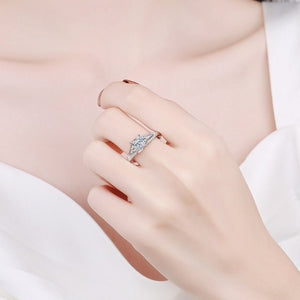 Hand wearing a silver ring with a diamond on a light background