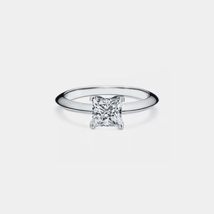 A princess cut moissanite engagement ring with a solitaire design, set in a metal band possibly sterling silver with platinum plating.