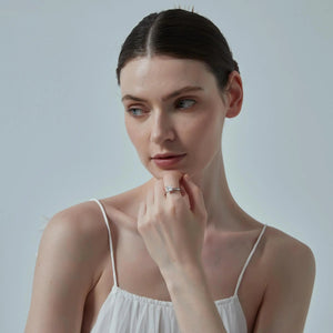 Woman wearing a white dress with thin straps against a light gray background