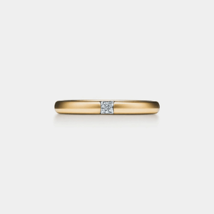 Gold ring with a diamond on a light gray background