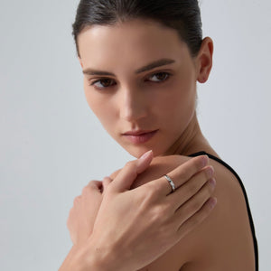 Woman wearing a silver ring on her finger against a plain background