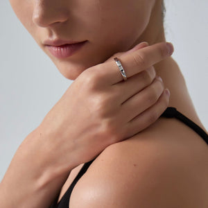 Close-up of a woman wearing a silver ring on her finger against a neutral background