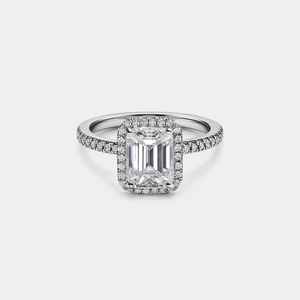 Diamond ring with emerald-cut center stone on a light gray background