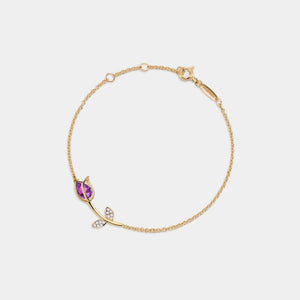 Gold bracelet with purple gemstone and heart-shaped charm on a white background