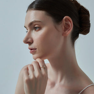 Woman with a bun and a ring on her finger against a neutral background