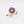 Gold ring with purple floral design and embedded diamonds on a light gray background