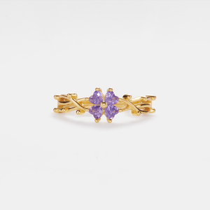 Gold ring with a purple gemstone on a light gray background