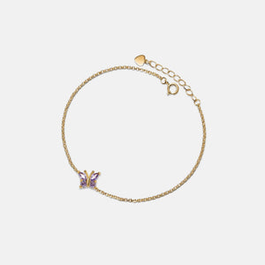 Gold bracelet with a butterfly charm on a light beige background