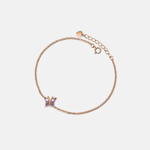 A gold-plated anklet with a charm depicting a butterfly, featuring a purple gemstone.
