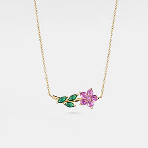 Gold necklace with a pink flower and green leaves pendant on a white background