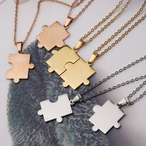Four puzzle piece necklaces in rose gold, gold, silver, and white on a textured fabric background.