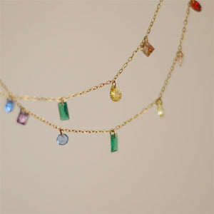 A gold-plated titanium steel necklace with multiple colorful gemstone charms, displayed on a white surface.