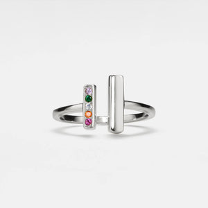 A gold-colored ring with a simple design featuring a wire band and multiple small, multicolored gemstones arranged in a line on one side.