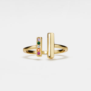 Gold ring with colorful gemstones on a light gray background