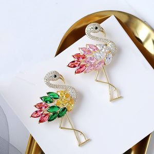 Colorful flamingo-shaped earrings on a white card with a gold base.