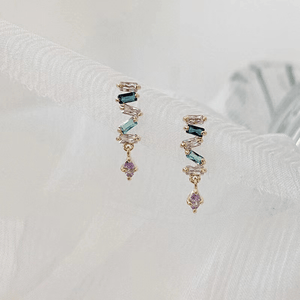 Multicolored gemstone earrings on a textured white surface