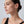 Close-up of a woman wearing a small hoop earring on a light gray background