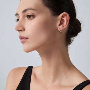 Close-up of a woman wearing a small hoop earring on a light gray background