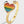 Gold ring with a rainbow heart design on a light gray background