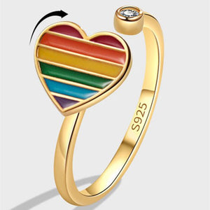 Gold ring with a rainbow heart design on a light gray background