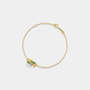 Gold bracelet with green gemstones on a light gray background