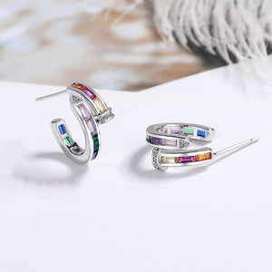 Silver hoop earrings with colorful gemstones on a white surface