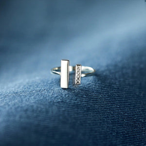 Silver ring with geometric design on a blue textured fabric background