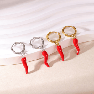Four pairs of earrings with red chili pepper charms on a light pink background