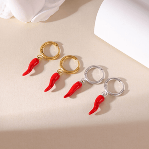 Pair of earrings with red chili pepper designs on a beige surface