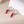 Earrings with red chili pepper-shaped charms on a beige surface