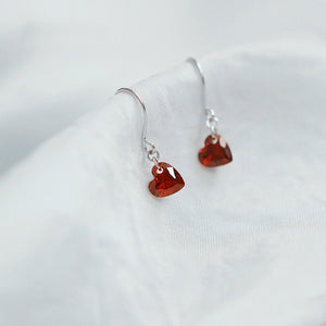 Heart-shaped red earrings on a white background
