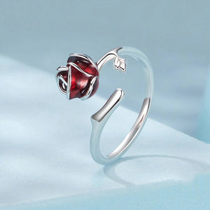 Silver ring with a red gemstone rose on a light blue background