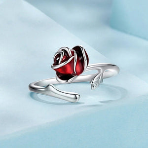 Silver ring with a red rose design on a light blue background