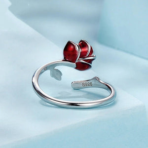 Silver ring with a red flower-shaped design on a light blue background