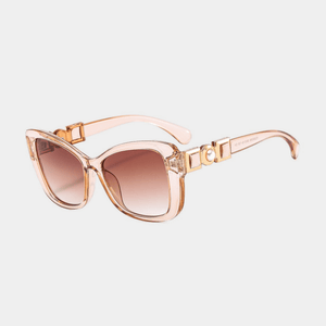 Sunglasses with a rose gold frame and brown gradient lenses on a light gray background